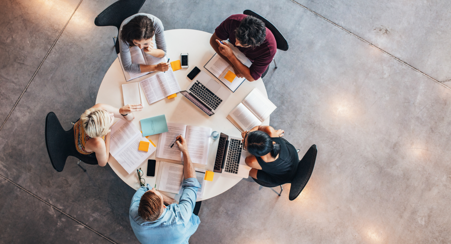 Overhead shot of students working at a table with books and laptops open